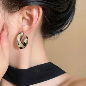 Close-up view of minimalist silver metallic C-shaped stud earrings with pleated texture