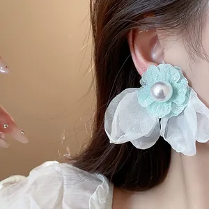 Close-up detail of mint green chiffon flower earring with large pearl center on ear