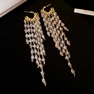 Gros plan d'élégantes boucles d'oreilles à pompons dorés et perles de cristal
