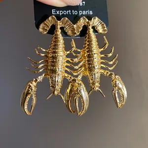 Close-up view of vintage gold lobster-shaped metal earrings with textured detail
