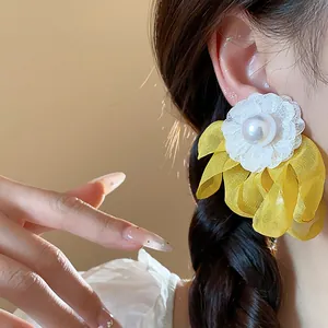 Close-up of yellow and white chiffon flower earrings with central pearl on model's ear