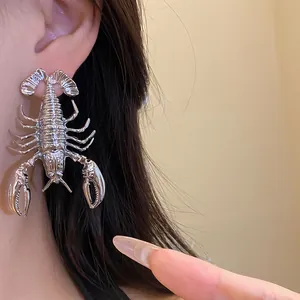 Detailed view of an oversized silver lobster-shaped metal statement earring worn on ear