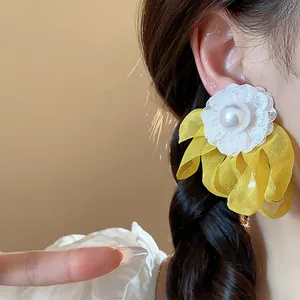 Detail of elegant chiffon flower earrings with white lace and central pearl accent