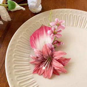 Dettaglio del fermaglio per capelli con giglio artificiale e petali rosa su piatto