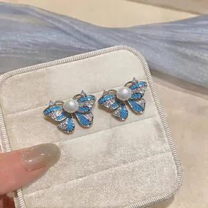Elegant butterfly stud earrings featuring white pearls and blue zircon stones in silver