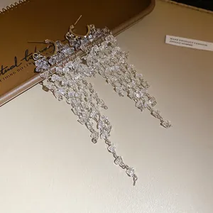 Vue détaillée de boucles d'oreilles créoles en C avec des pampilles en strass étincelantes.