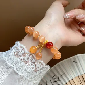 Close-up detail of the vintage orange cat's eye beaded bracelet with a red accent bead.