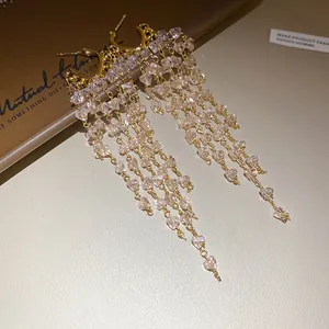 Gros plan sur des boucles d'oreilles créoles en C avec pompons en cristal rose.