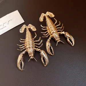 Close-up of gold metal lobster earrings with intricate vintage texture details