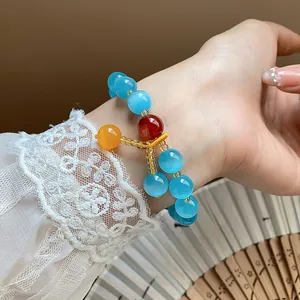 Close-up of blue cat-eye stone beaded bracelet with red and yellow accents on lace