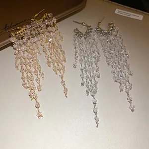 Vue détaillée d'élégantes boucles d'oreilles en C avec pampilles de cristal en or et en argent