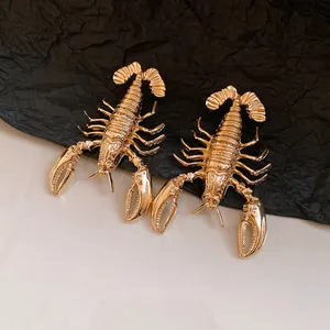 Macro view of retro gold-toned metal lobster earrings with intricate textured details