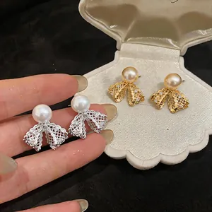 Primo piano dettagliato di orecchini a fiocco placcati oro 18K con perle e cristalli lucidi.