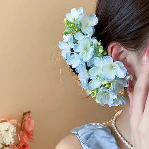Detailed close-up of a dreamy blue fabric flower hair pin worn by an elegant woman