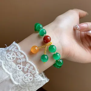 Detailed view of a vintage cat-eye stone beaded bracelet worn on a female wrist