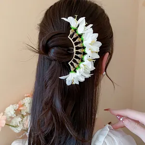 Detail view of an elegant white fabric flower hair fork styled in long brown wavy hair