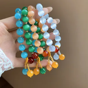 Detail view of colorful cat's eye stone beaded bracelets held in hand with golden beads