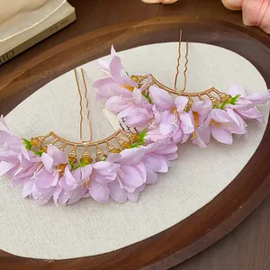 Close-up view of elegant purple fabric flower hairpins with golden metal U-shaped forks.