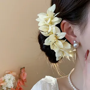 Detailed view of an elegant cream fabric flower hairpin accessory on a model's hair bun