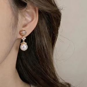 Elegant 18k gold plated lucky clover flower pearl drop earrings on a female model