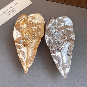 Dettaglio di squisite spille a forma di foglia oro e argento con design in cristallo