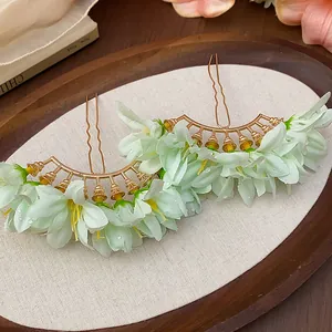 Macro view of elegant light green fabric flower hairpins with golden metal finish and water droplets