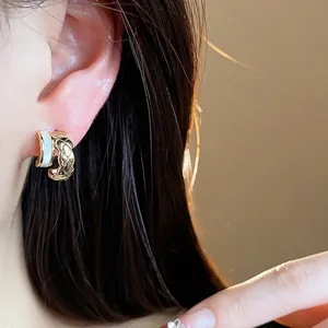Elegant 18k gold plated C-shaped hoop earrings with quilted pattern worn by model