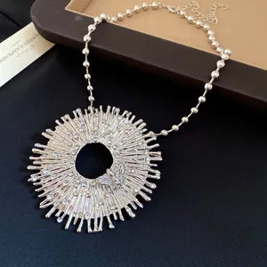 Macro detail of a vintage silver sunburst pendant with crystal bees on a bead chain.