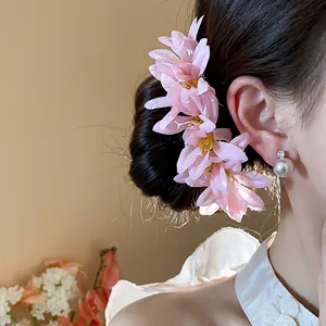 Macro detail of an elegant pink fabric flower hair pin worn on a stylish updo hair.