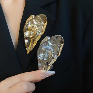 Dettaglio delle spille artistiche a forma di foglia e orecchio in oro e argento.
