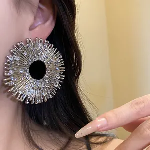 Macro view of a large sparkling rhinestone sunburst statement earring worn on a model's ear