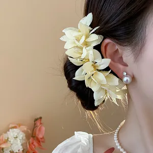 Close-up view of elegant yellow fabric flower hair clip with pearl earring and necklace