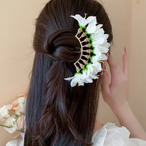 Back view of a model wearing a delicate fan-shaped hair pin with white fabric flowers.