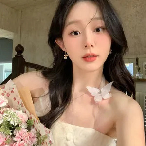 Elegant pearl floral drop earrings worn by a model holding flowers in a romantic setting