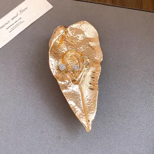 Primo piano di spilla a foglia d'oro artistica con dettaglio orecchio e strass