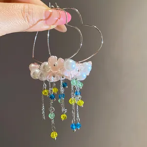 Macro view of flower and pearl details on heart-shaped tassel earrings