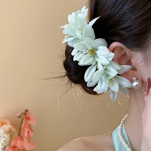 Close-up of an elegant mint green fabric flower hair pin with pearl ornament on a model.