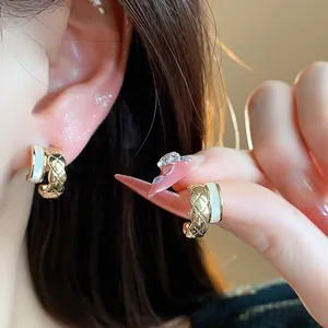 Detailed view of 18k gold-plated C-shaped stud earrings with quilted lattice design.