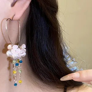 Detail view of heart-shaped hoop earrings with pearl flowers and colorful tassels