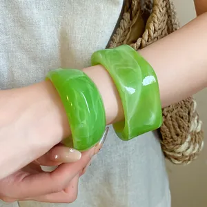 Primo piano dettagliato che mostra braccialetti in acrilico marmorizzato verde al polso