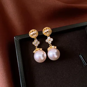 Detailed view of elegant vintage pearl drop earrings with sparkling flower accents in gold