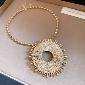 Close-up of gold-colored sunburst pendant necklace with rhinestones and bee detail
