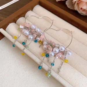 Detailed macro view of heart-shaped hoop earrings with pearls and floral tassels