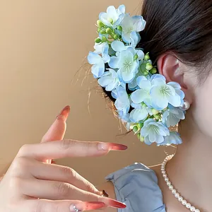 Detail view showing elegant light blue fabric floral headpiece with pearl accents on model