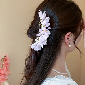 Detail view of a delicate pink fabric flower hairpin worn by an Asian model in an elegant bun