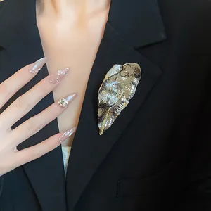 Primo piano di una grande spilla a foglia d'argento sul bavero di un blazer nero