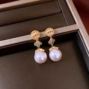 Close-up of 18k gold plated lucky flower pearl earrings in a jewelry box.