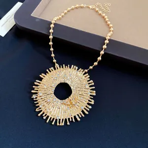 Detailed macro shot of a gold sunburst circular pendant necklace featuring a rhinestone bee