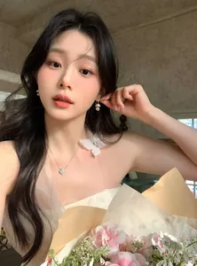 Elegant model wearing luxury pearl flower tassel earrings and a sparkling clover necklace