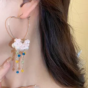 Detail view of heart hoop earring with pearl flowers and colorful crystal tassels